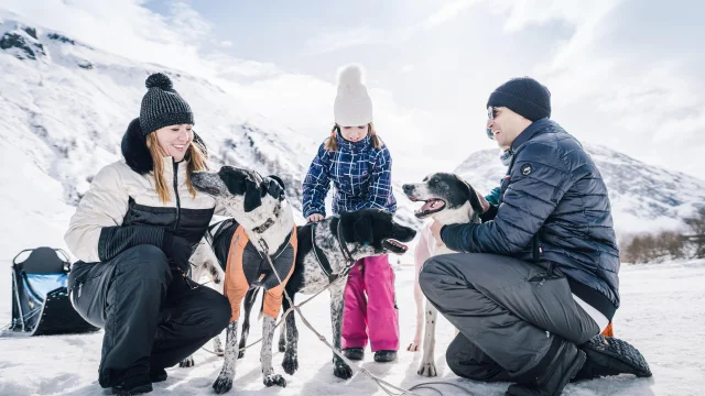 Famille avec enfants qui caresse les chiens de traineau dans la vallée du Manchet à Val d'Isère