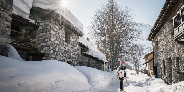 Una sciatrice che si muove nel villaggio con gli sci in spalla in Val d'Isère in inverno a Le Laisinant